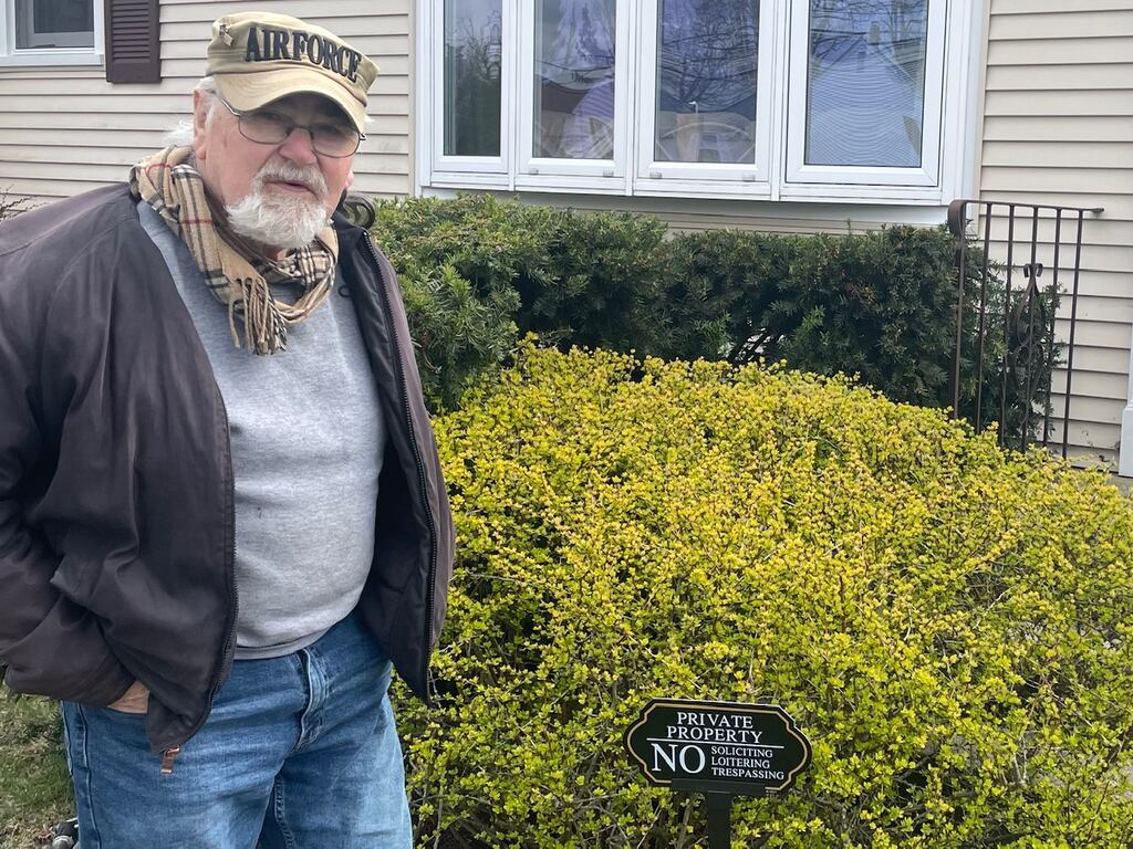 Donald S. Fife stands next to his new lawn sign, which reads, 