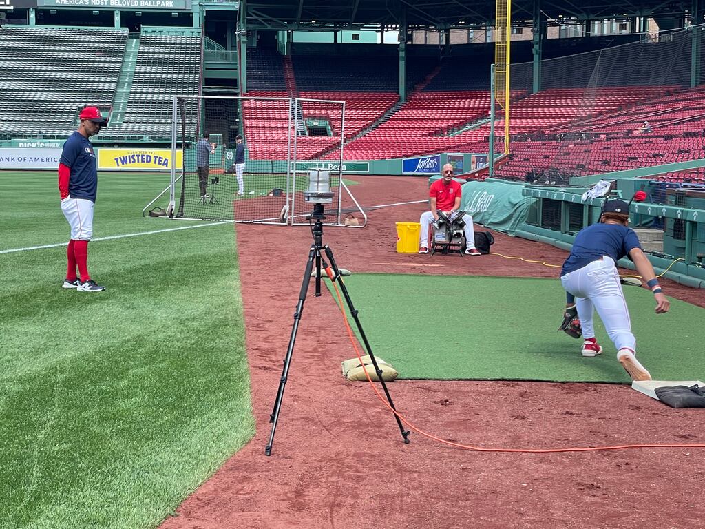 Red Sox manager Alex Cora (left) watches Kristian Campbell work with infield coach José Flores (seated) to see how the rookie handled playing first base before Friday's game against the Braves at Fenway Park.