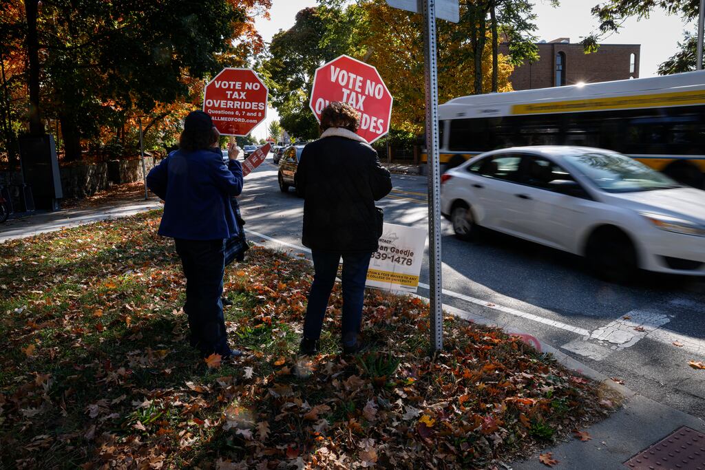 In Medford, opponents of a tax override held Vote No Tax Overrides signs in 2024. The measures passed in November. 
