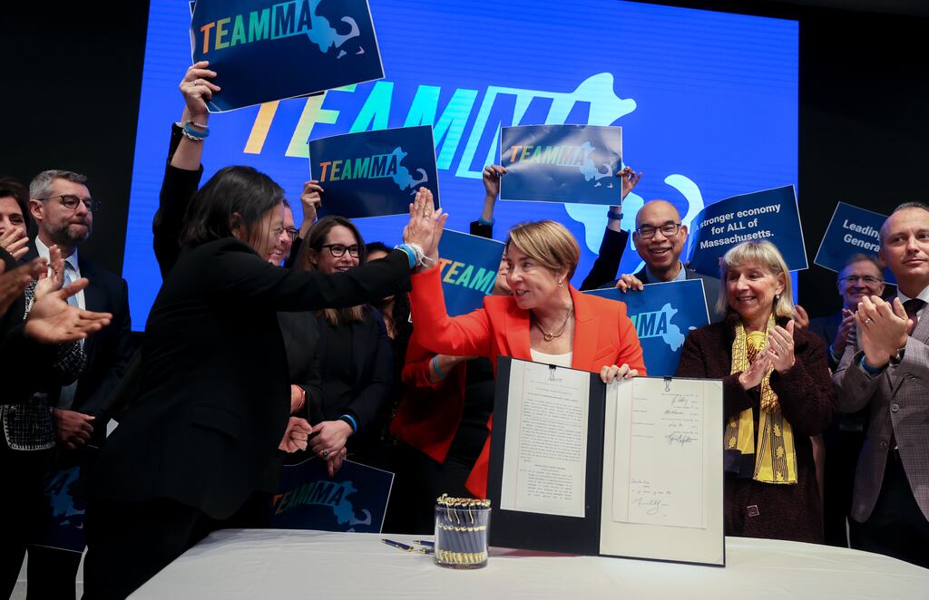 Yvonne Hao, left, gave Governor Maura Healey a high-five after Healey did a ceremonial signing of a $4 billion economic development package at the Ragon Institute in Cambridge on Dec. 10, 2024.