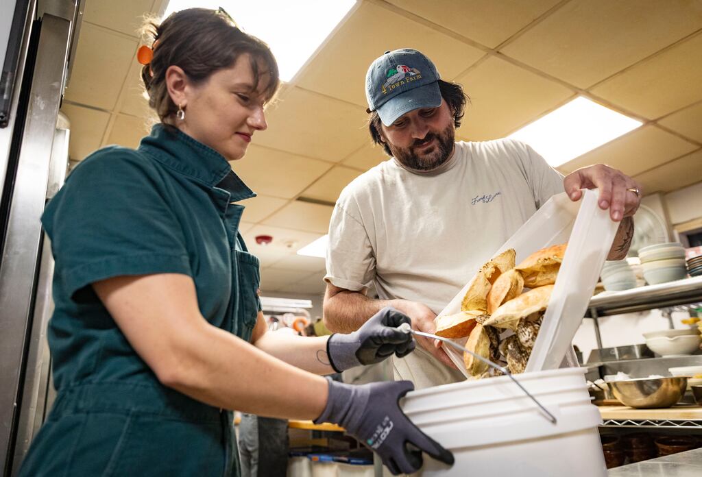 Felicia Neuhof, left, collects shell waste from Eric Brown, owner and chef of the restaurant Frank & Laurie's, on April 25, in Providence, R.I.