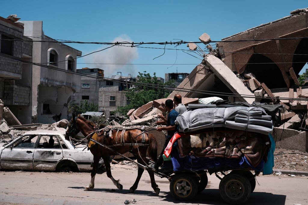 Smoke rose to the sky following an Israeli airstrike, as Palestinians fleeing Jabalia moved with their belongings on Friday.
